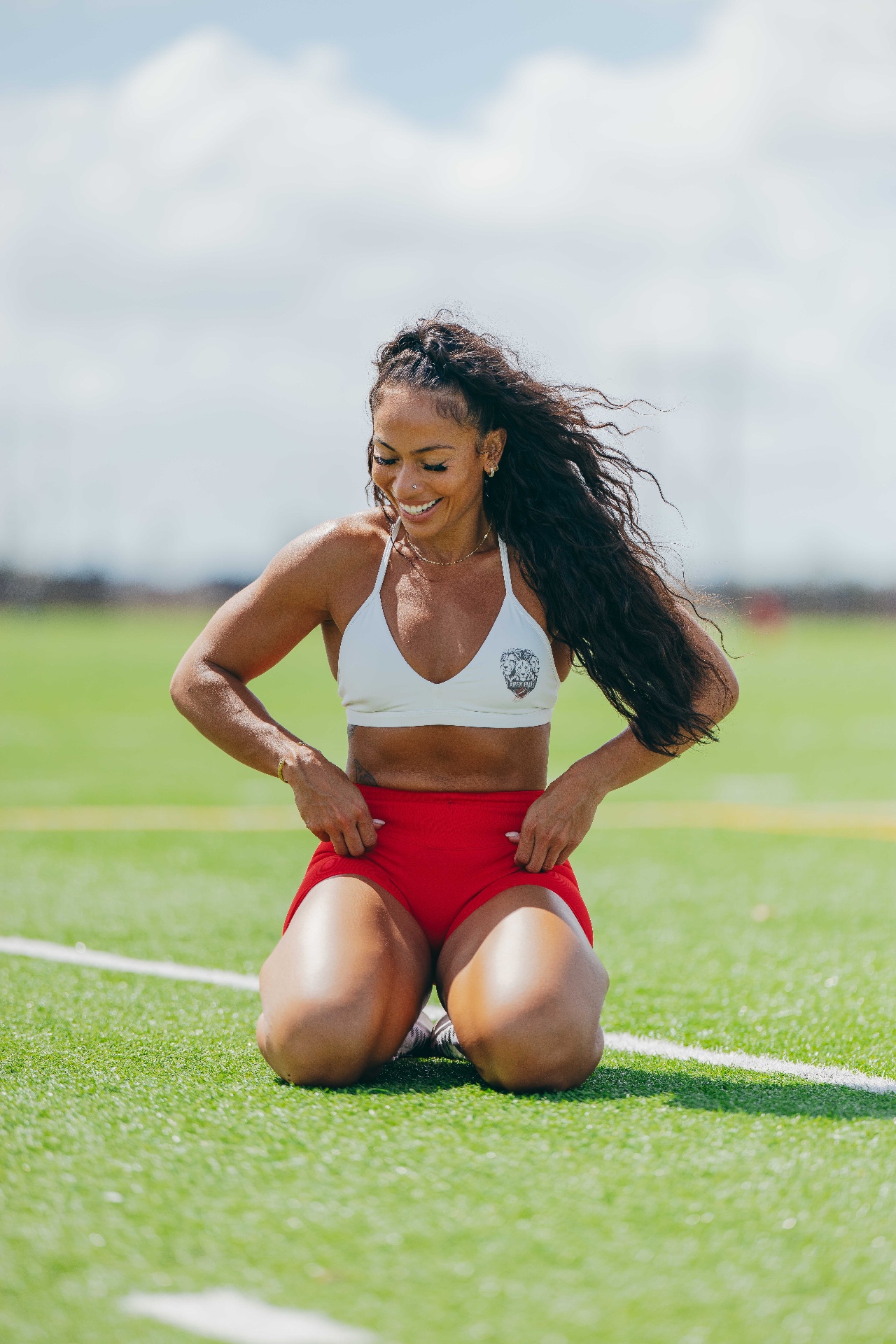 LabellaBeast founder and coach kneeling on a sunlit turf field in training gear
